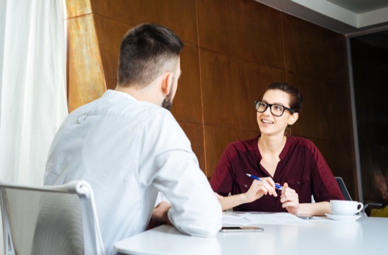 Real estate professional discussing property details with a client across a table